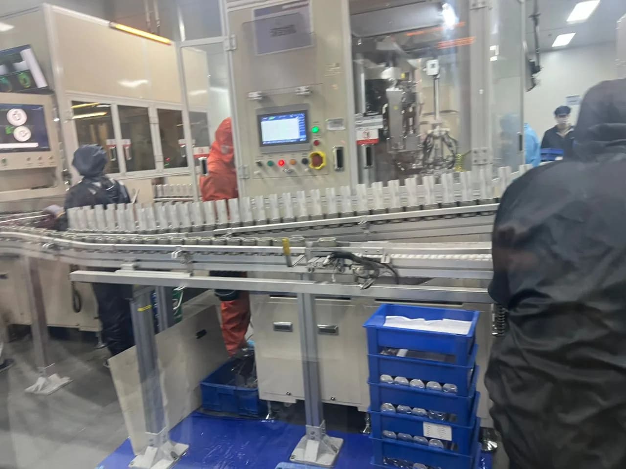 Factory workers monitoring an automated battery manufacturing line.