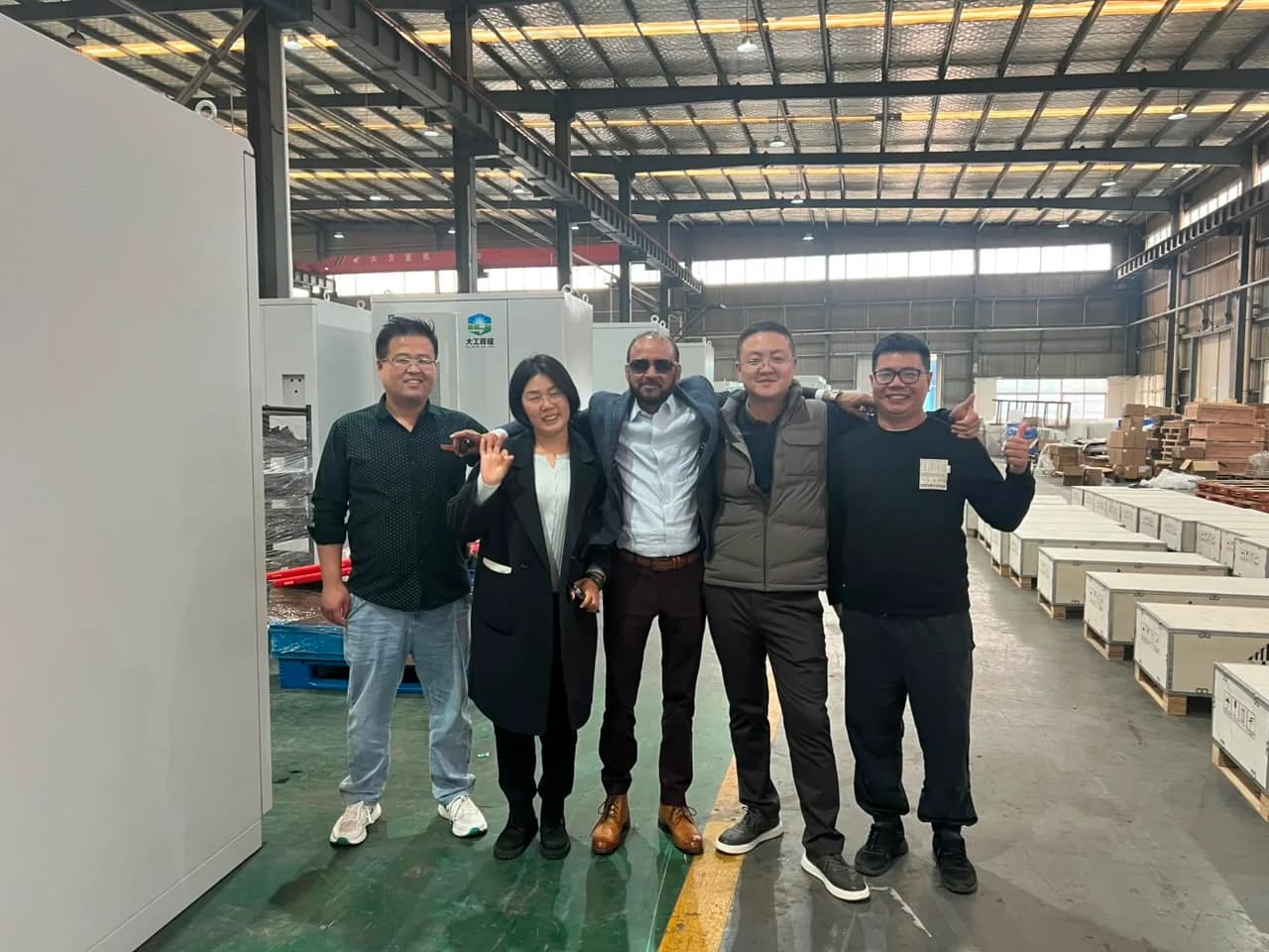 Rongkai Solar team and international partners posing on a battery factory production floor.