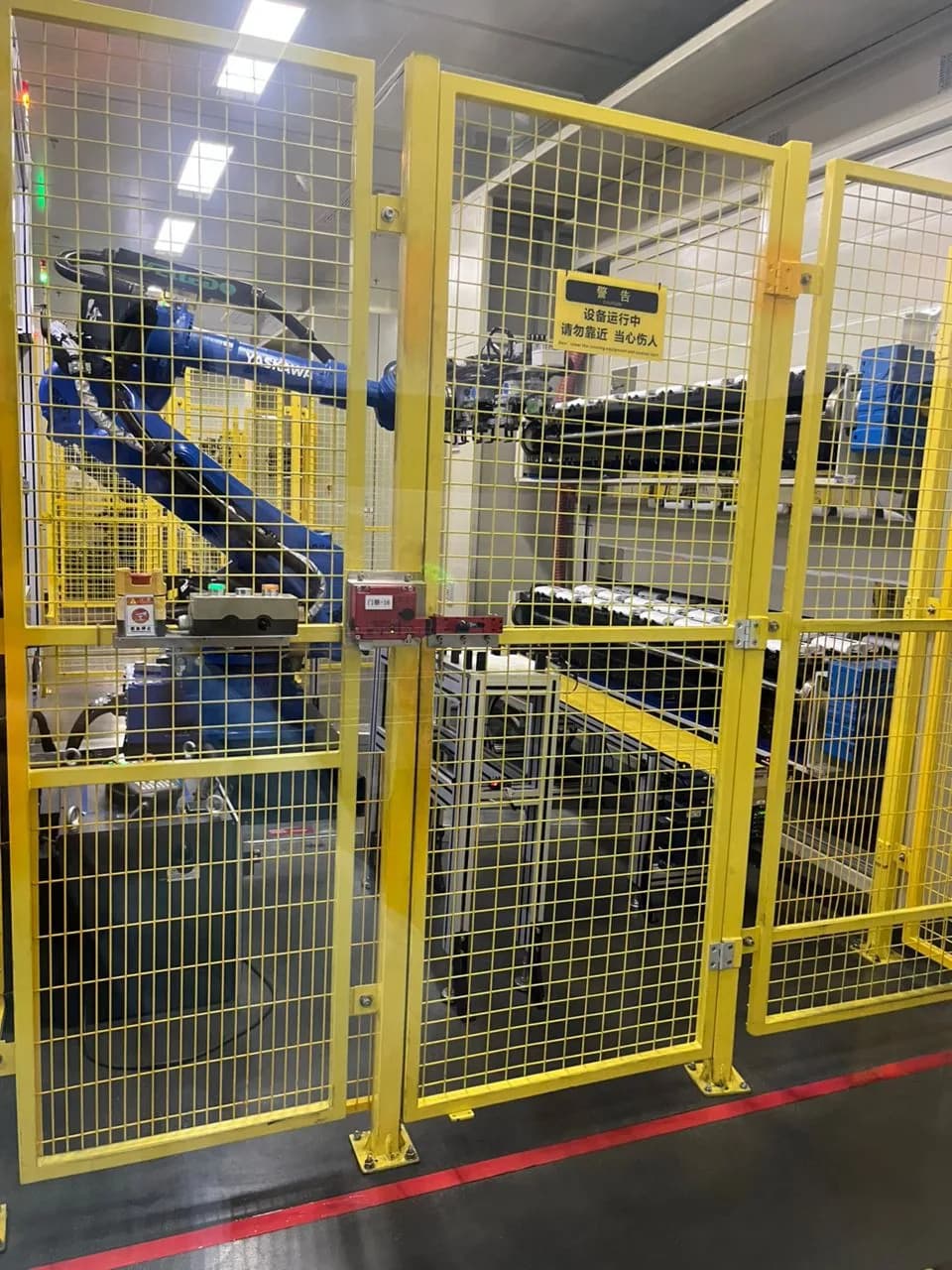 Robotic equipment operating behind safety fencing on a battery pack assembly line.