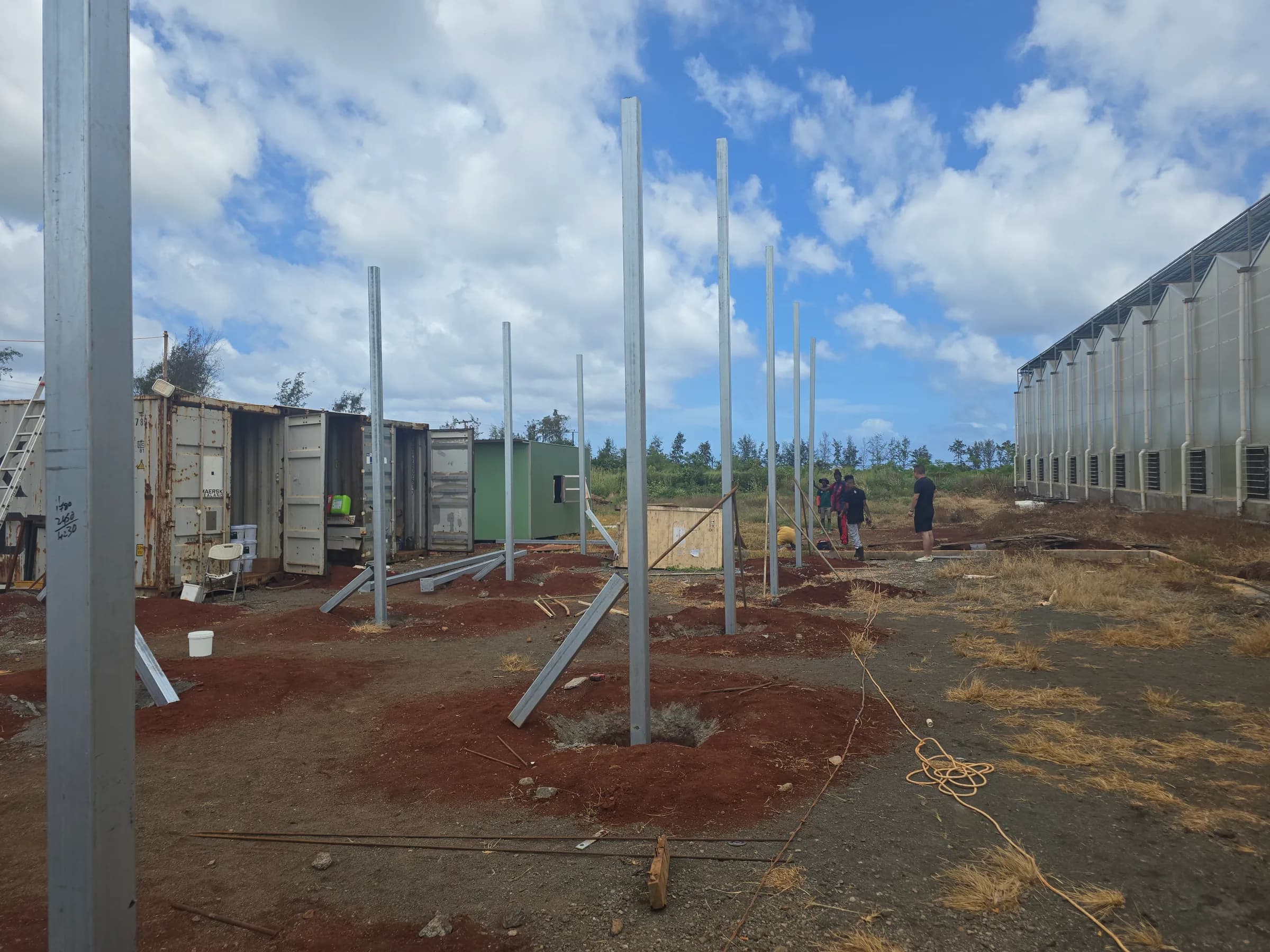 Project team inspecting steel mounting posts during construction of a solar installation.